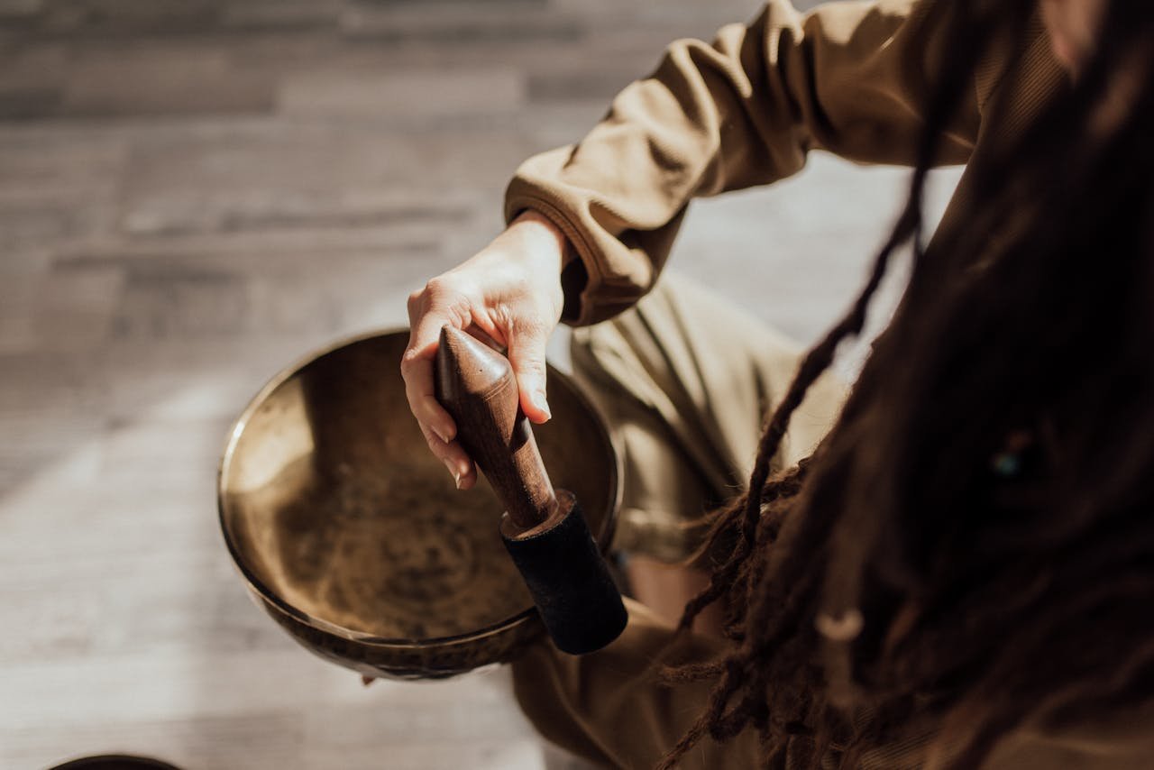 Close-up of a person using a singing bowl, demonstrating meditation sound therapy.